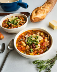 Two bowls of minestrone soup in white bowls with Isernio's chicken sausage