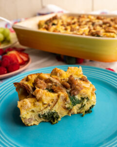 Breakfast strata on a blue plate featuring eggs, bread, spinach and Isernio's breakfast sausage