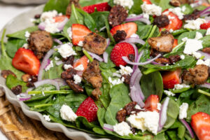 Large tray of spinach salad topped with grilled Isernio's chicken, strawberries, feta and onions.