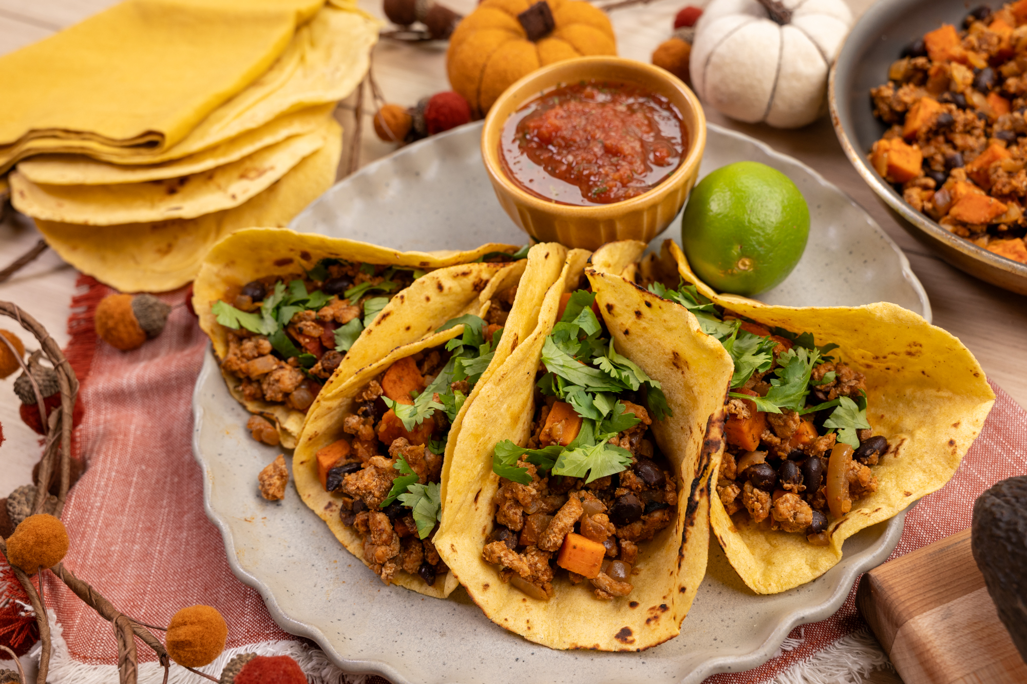 A plate of tacos that are made with Isernio's ground chicken, sweet potatoes and black beans. Served in corn tortillas with chips and a lime.