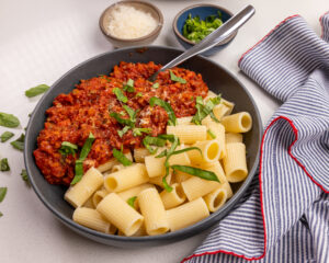 A bowl of chicken bolognese pasta sauce served with pasta.