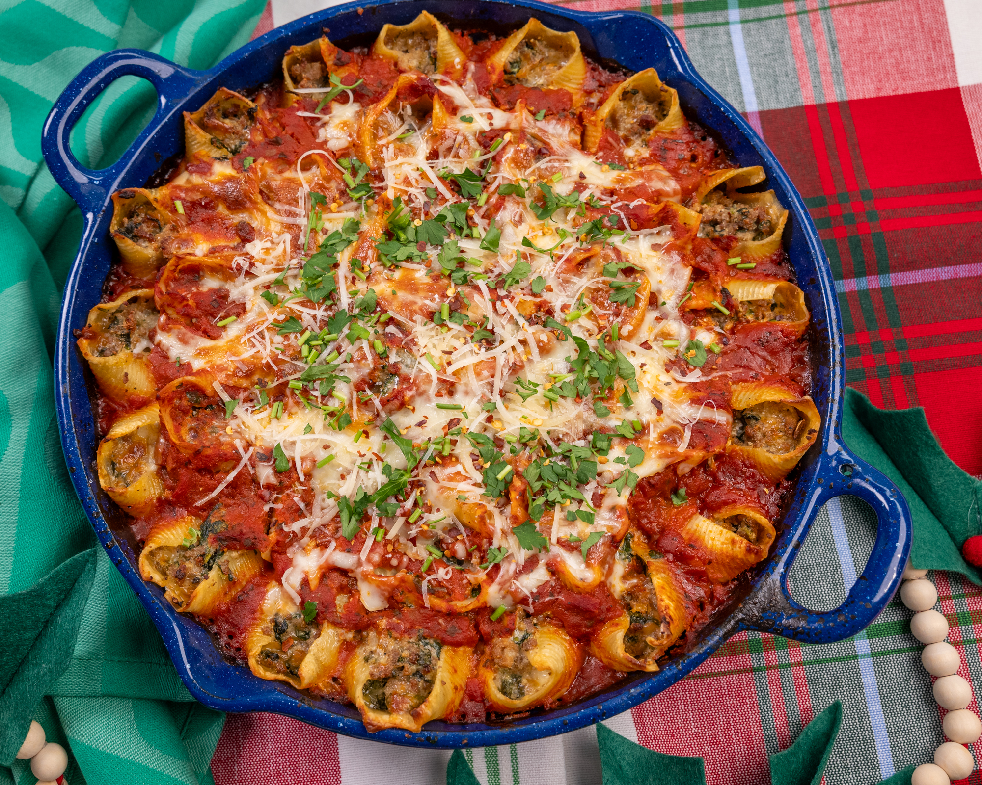 A casserole of stuffed pasta shells with a red sauce. The shells are filled with Isernio's Italian Sausage.