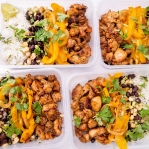 Meal preparation of four Tupperwares filled with Isernio's marinated chicken thighs, black beans, cilantro-lime rice and cooked bell peppers.