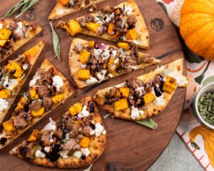Grilled flatbread topped with Isernio's sausage, butternut squash and goat cheese. Fall decorations set the table.