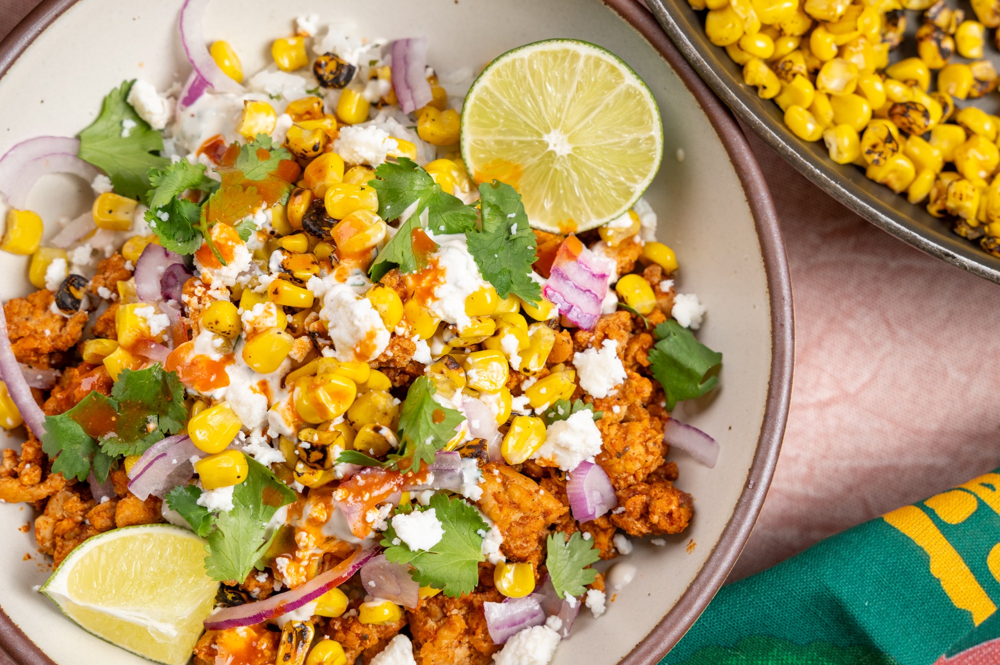 Isernio's Street Corn Ground Chicken Protein Bowl topped with charred corn, cotija cheese, cilantro, red onion, creamy street corn sauce, and fresh lime over cilantro-lime rice.