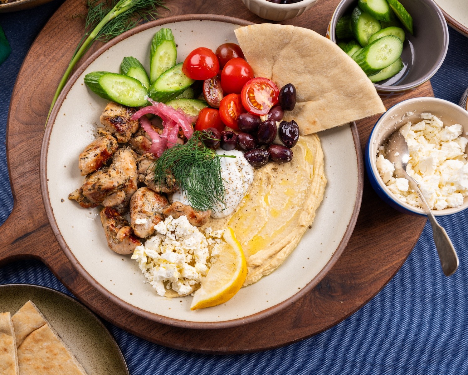Loaded Garlic Herb Chicken Hummus Plate with Isernio’s Garlic Herb Chicken Thighs, hummus, cucumbers, cherry tomatoes, feta, Kalamata olives, pickled red onions, fresh dill, lemon, and warm pita.